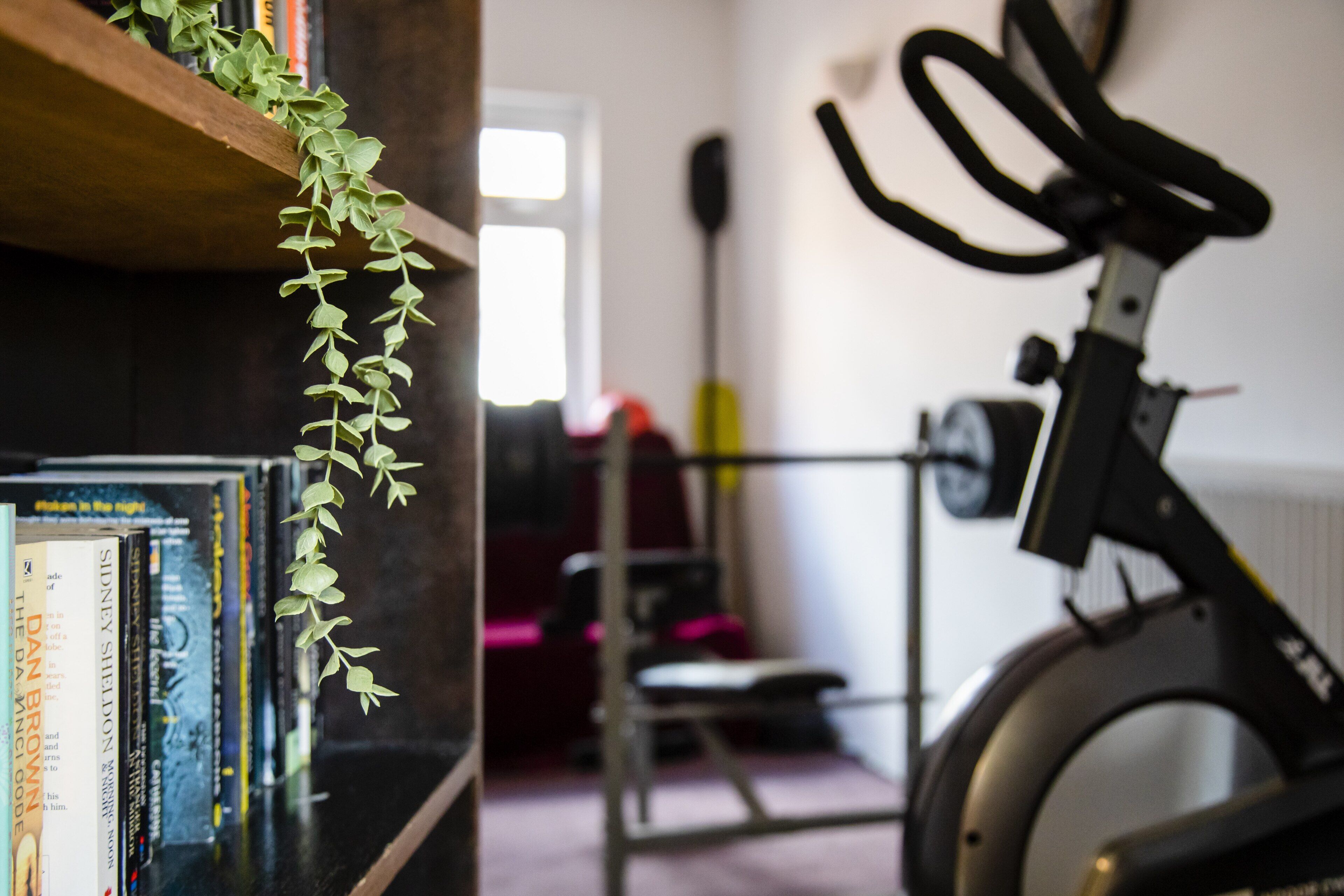 A room with a bookshelf, a stationary bike, and a door in the background.