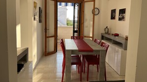 A dining area with a table and chairs, a kitchen counter, and a clock on the wall. - MELOGRANO apartment near sandy beach (Campomarino)