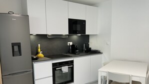 Une cuisine moderne équipée d’un réfrigérateur, d’une cuisinière, d’un four et d’une petite table à manger avec des chaises.
