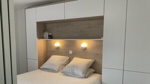 Une chambre à coucher avec un lit, deux lampes de chevet et une étagère au-dessus du lit.