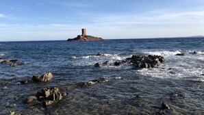 Un paysage côtier avec une rive rocheuse et une tour sur une petite île.
