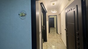 Un pasillo con un letrero que indica un baño, una lámpara en el techo y una puerta al final.