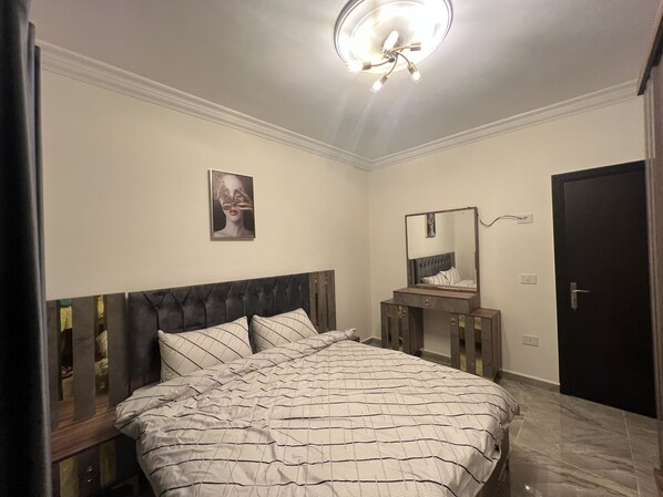A bedroom with a bed, a bedside table, a mirror, and a door. - NH Guest House Zefta - First Floor Apt (Zefta)