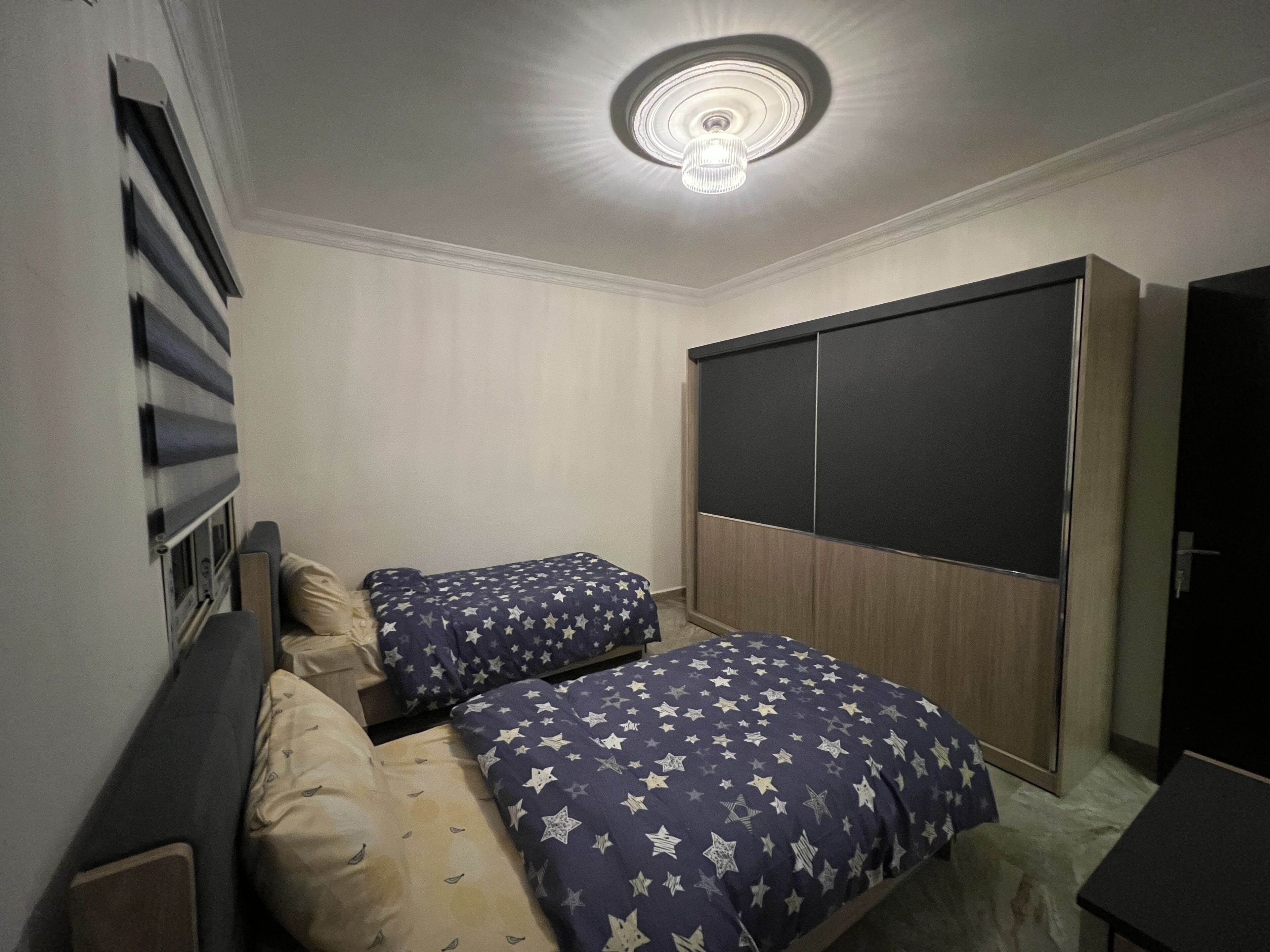 Un dormitorio con dos camas, un armario y una lámpara en el techo.