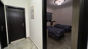 Un pasillo que conduce a un dormitorio con ventilador de techo, una cama con colcha estampada de estrellas y un cuadro en la pared.