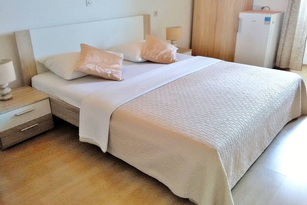 A neatly made bed with a white headboard, two pillows, and a textured blanket.