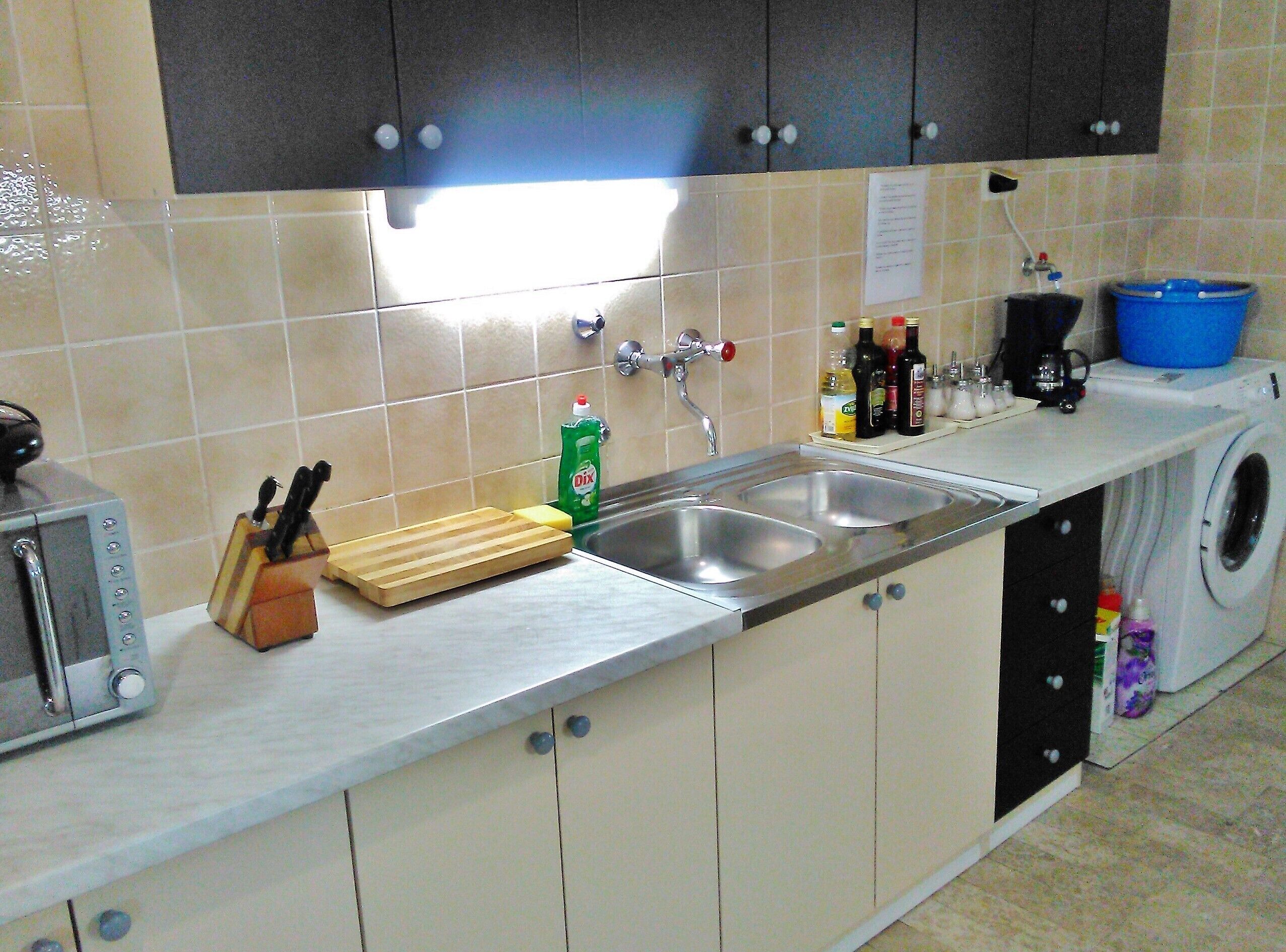 A compact kitchen with a sink, a toaster, and a washing machine.