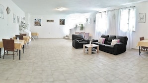 A spacious room with a large sofa, two armchairs, a small table, and a dining area with a table and chairs.