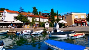 A waterfront area with boats docked, buildings, and people walking.