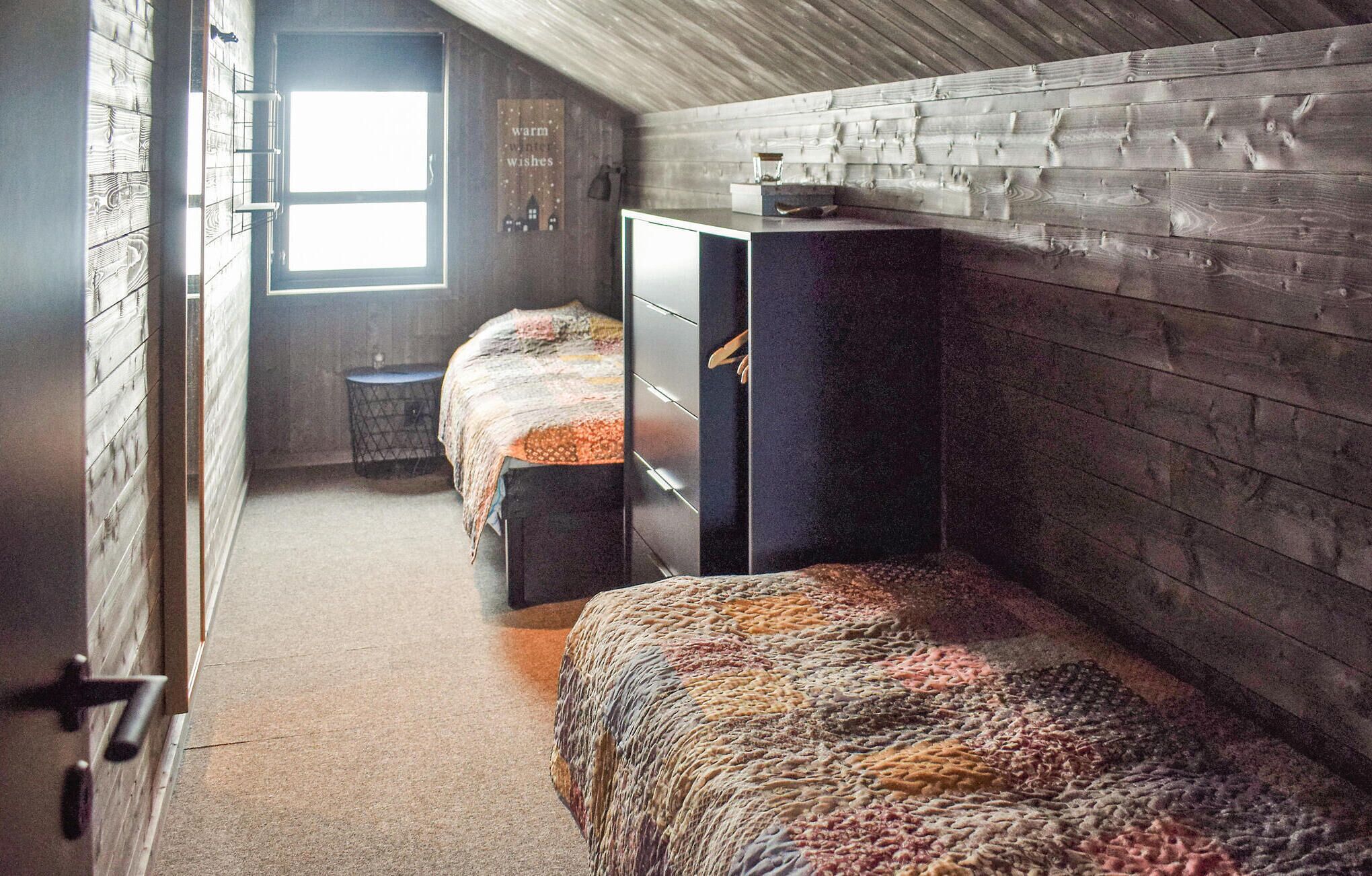 Une pièce confortable avec deux lits, des murs en bois, une fenêtre et une petite table.