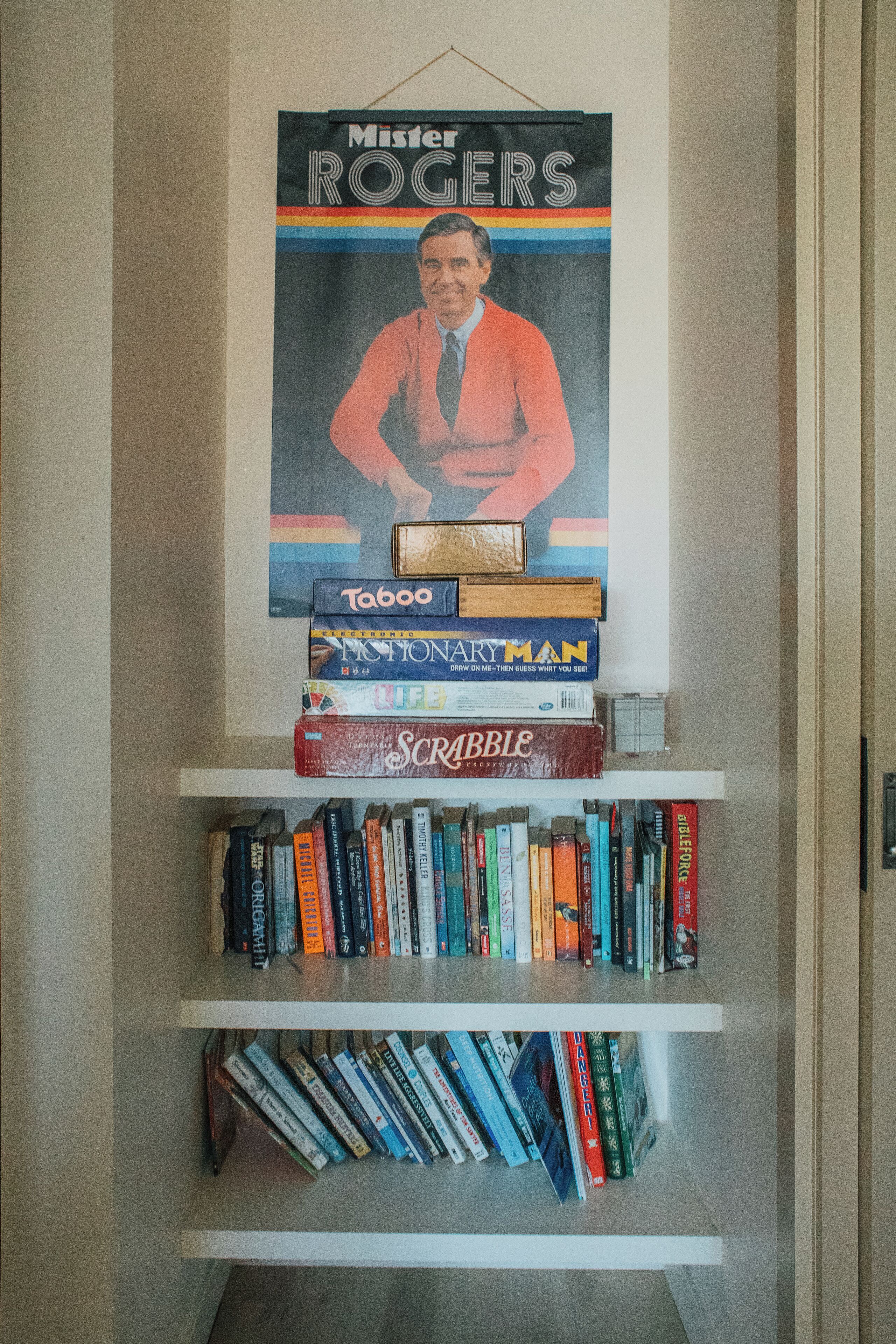 En reol med et plakat af Hr. Rogers hængende over.