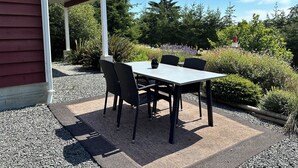 An outdoor patio with a table and chairs, surrounded by gravel and plants. - Cozy and Private West Coast Home (Sooke)