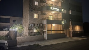 Ein mehrstöckiges Gebäude mit einem Schild, auf dem „Guest House“ steht. Es hat eine Steinfassade, mehrere Fenster und Klimaanlagen.