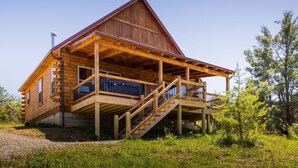 A wooden log cabin with a covered porch and a staircase leading to the entrance.