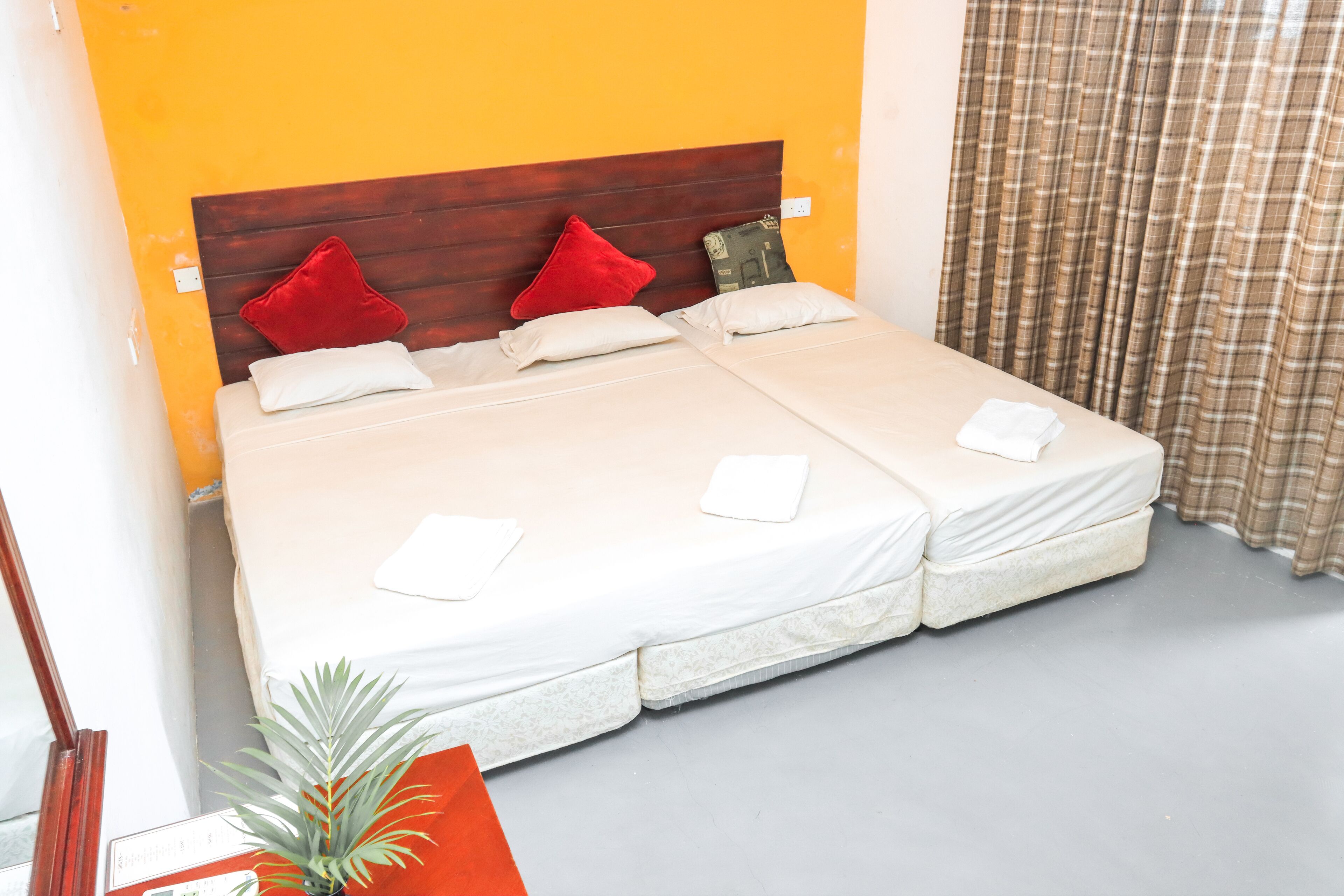 A double bed with a wooden headboard, two red pillows, and two white pillows.