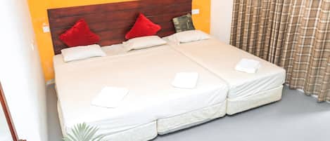 A double bed with a wooden headboard, two red pillows, and two white pillows.