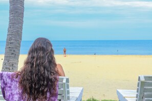 Na praia, espreguiçadeiras, guarda-sóis, toalhas de praia 