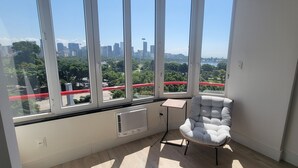 A room with large windows offering a city view, a radiator, a small table, and a chair. - Ocean and City Views (Rio de Janeiro)