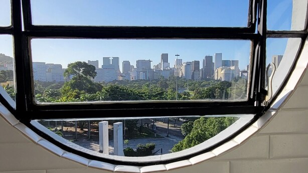 A round window with a view of a cityscape through a brick wall. - Ocean and City Views (Rio de Janeiro)