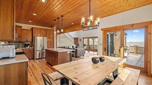 A spacious kitchen with wooden cabinets, a stainless steel refrigerator, and a wooden dining table with benches. - Private Community~5 Bedrooms~Loaded~Amazing Mountain View’s-Jacuzzi-Game Room (Seven Devils)