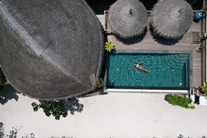 An aerial view of a swimming pool with two thatched umbrellas, surrounded by a wooden deck and greenery. - Island Luxury Boutique Hotel - Fulhadhoo (Fulhadhoo)