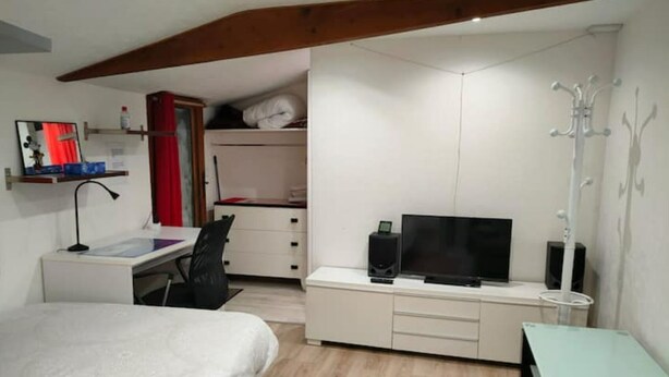 Ein gemütliches Schlafzimmer mit Bett, Schreibtisch, Fernseher und Kleiderschrank.