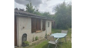 Ein rustikales Haus mit einer kleinen Veranda, einem Tisch und Stühlen davor sowie einem Fahrrad im Hintergrund.
