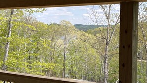 Une terrasse en bois offrant une vue sur une zone boisée et des collines en arrière-plan.