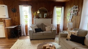 A cozy living room with a sofa, a coffee table, and a dining area with a table and chairs. - Dog Friendly Lakefront Cabin with Amazing Sunset Views & New Boat dock.  (Jefferson City)