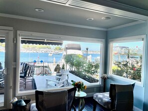 A room with a view of the sea, a dining table, and two chairs.