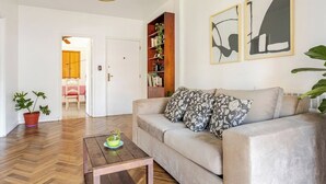 Ein Wohnzimmer mit einer Couch, einem Couchtisch, einem Bücherregal und einer Topfpflanze.