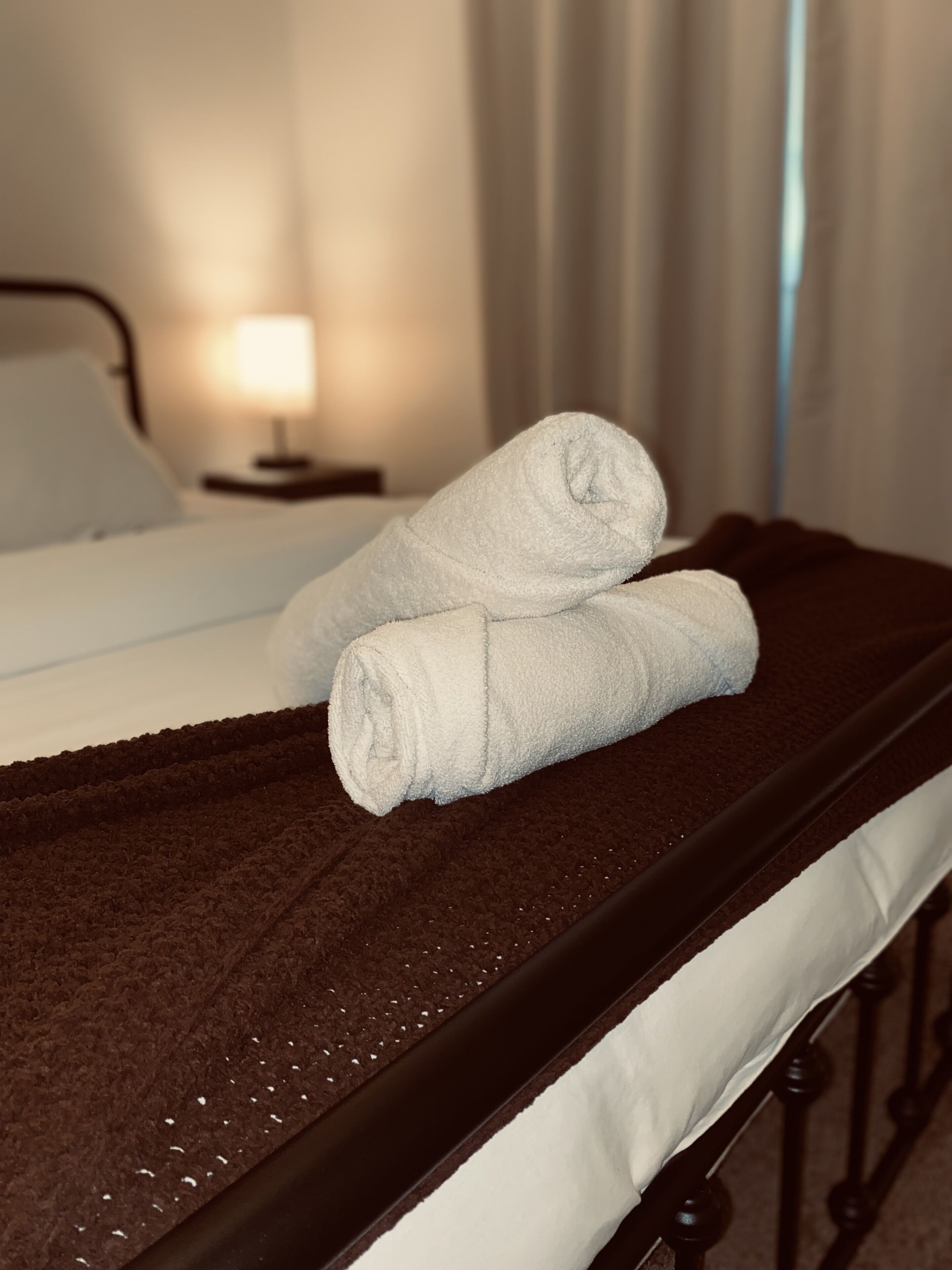 Una cama bien hecha con sábanas blancas y una colcha marrón.