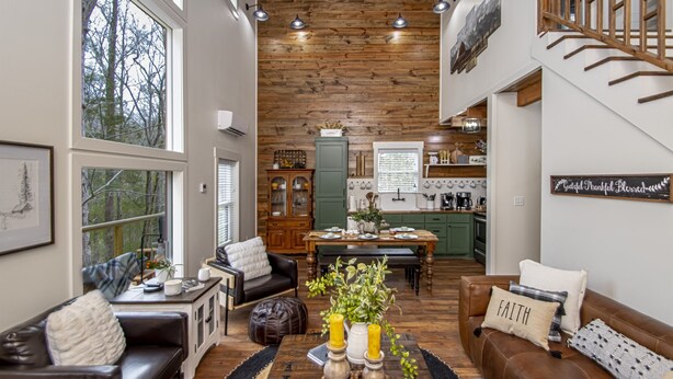A spacious living room with a wooden ceiling, a dining area, and a kitchen with green cabinets. - Couples Tree Loft  Rock Hot Tub Buffalo River (St Joe)