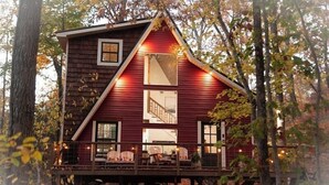 A cabin with a wooden exterior, a balcony with seating, and a staircase leading to the upper level. - Couples Tree Loft  Rock Hot Tub Buffalo River (St Joe)