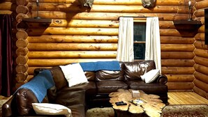 A log cabin interior with a leather sofa, a patterned rug, and deer antlers mounted on the walls. - Clean Log Cabin in Trout Fishing mecca!!!! (Genoa)