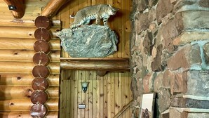 A wooden cabin interior with a stone wall, a wooden staircase, and a lynx mounted on a rock. - Clean Log Cabin in Trout Fishing mecca!!!! (Genoa)