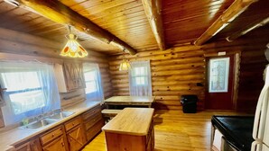 A log cabin interior with a kitchen area, wooden floors, and a central island. - Clean Log Cabin in Trout Fishing mecca!!!! (Genoa)