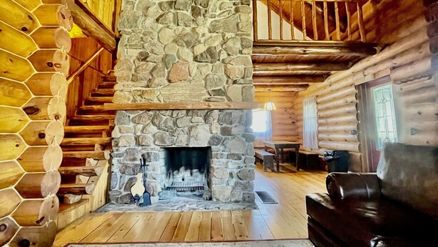 A log cabin interior with a stone fireplace, wooden staircase, and a patterned rug. - Clean Log Cabin in Trout Fishing mecca!!!! (Genoa)