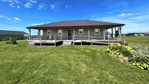 Une maison de plain-pied avec un porche, une petite terrasse et une pelouse bien entretenue.