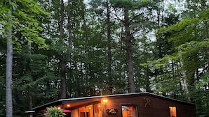 Een rustieke houten chalet met een veranda en een pad van stenen dat naar de ingang leidt.