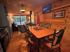 A wooden interior with a dining table, chairs, a television, and a fireplace. - šSaratoga Track & Streamside Retreat š² - Relax, Hike, Shop & Dine! (Greenfield Center)
