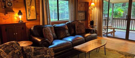 A cozy cabin interior with a leather sofa, patterned armchair, and a wooden coffee table.