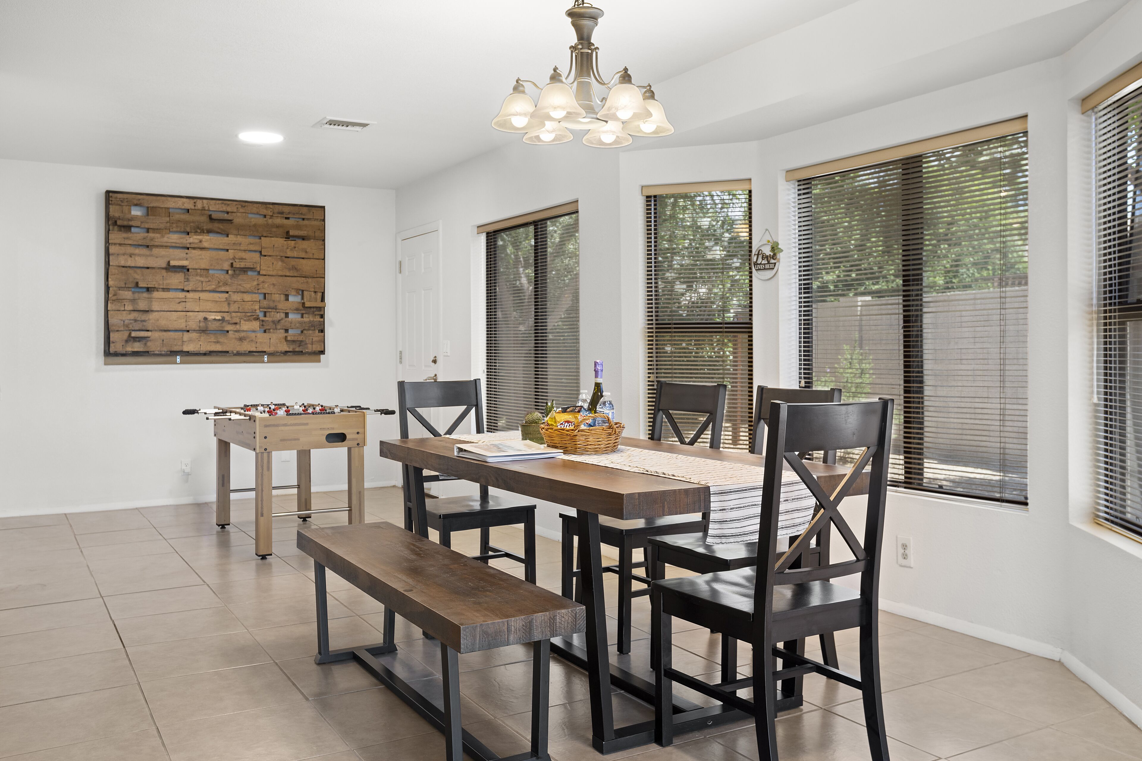 A dining area with a wooden table, black chairs, a bench, and a foosball table.