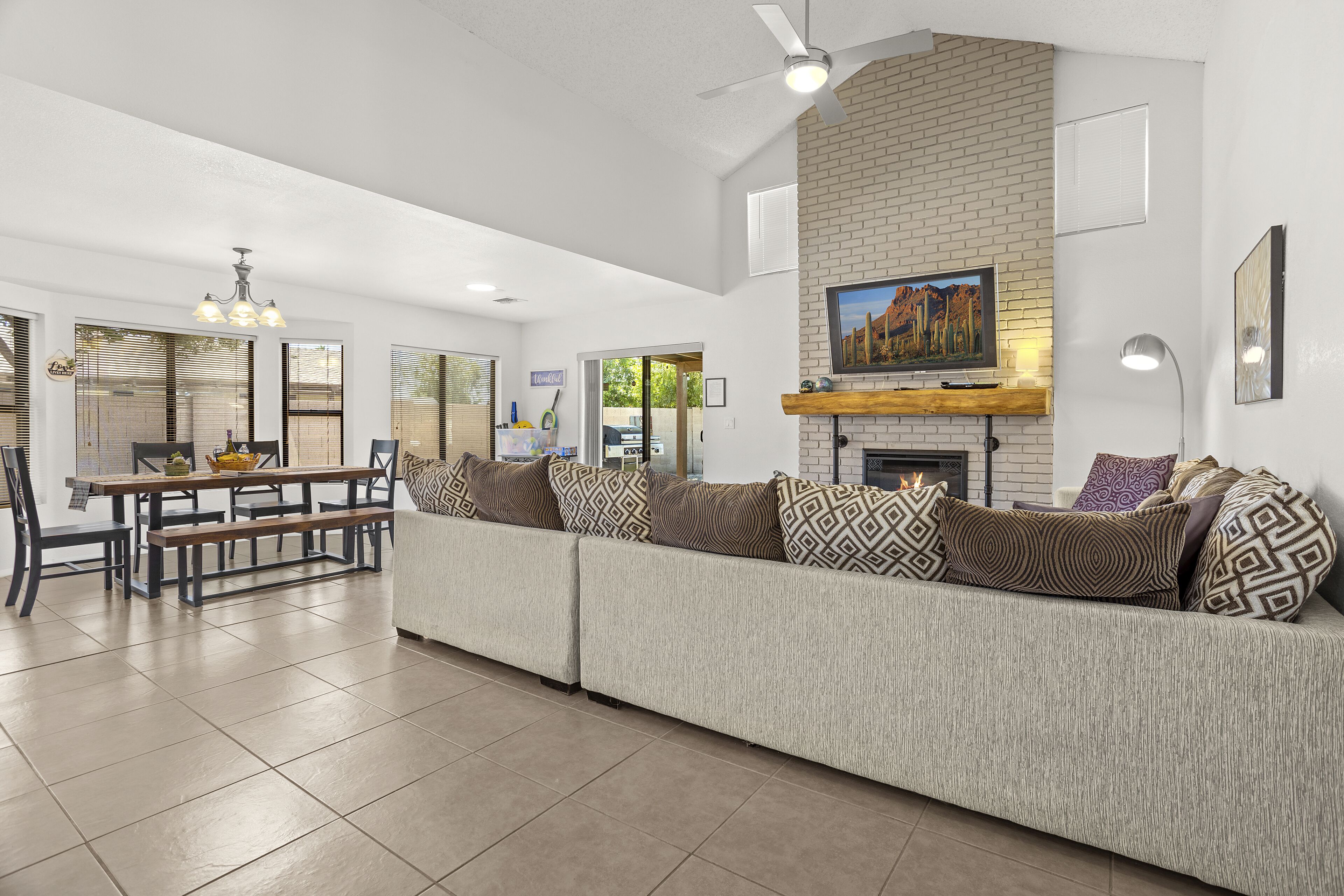 A modern living room with a sectional sofa, a dining table, and a fireplace.