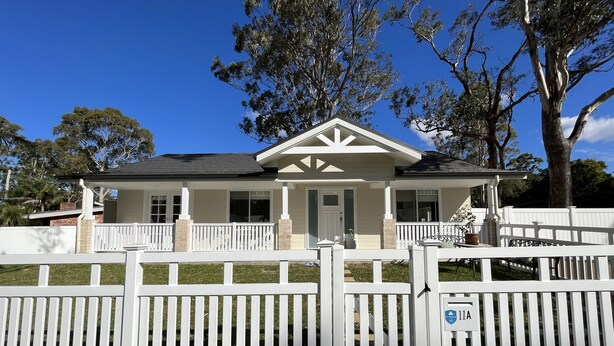 A two-story house with a front porch, a garage, and a white picket fence. - Hunter Valley guest house (Nulkaba)