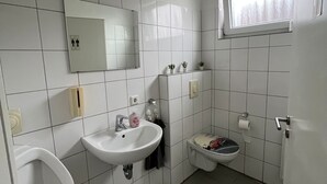 A small, clean bathroom with white tiles, a sink, a toilet, and a mirror. - Apart Rom Hannover Centrum (Hannover)