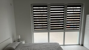 Une chambre à coucher avec un lit, une table de chevet et une fenêtre avec des stores.