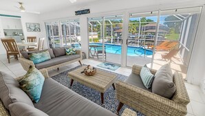 A spacious living area with a pool view, wicker furniture, and a dining area.