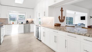 A modern kitchen with white cabinets, granite countertops, and a large island.