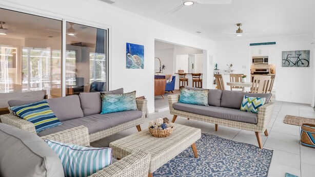 A spacious living area with wicker sofas, a coffee table, and a dining area with wooden furniture.